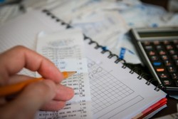 hand tallying receipts with pencil and calculator